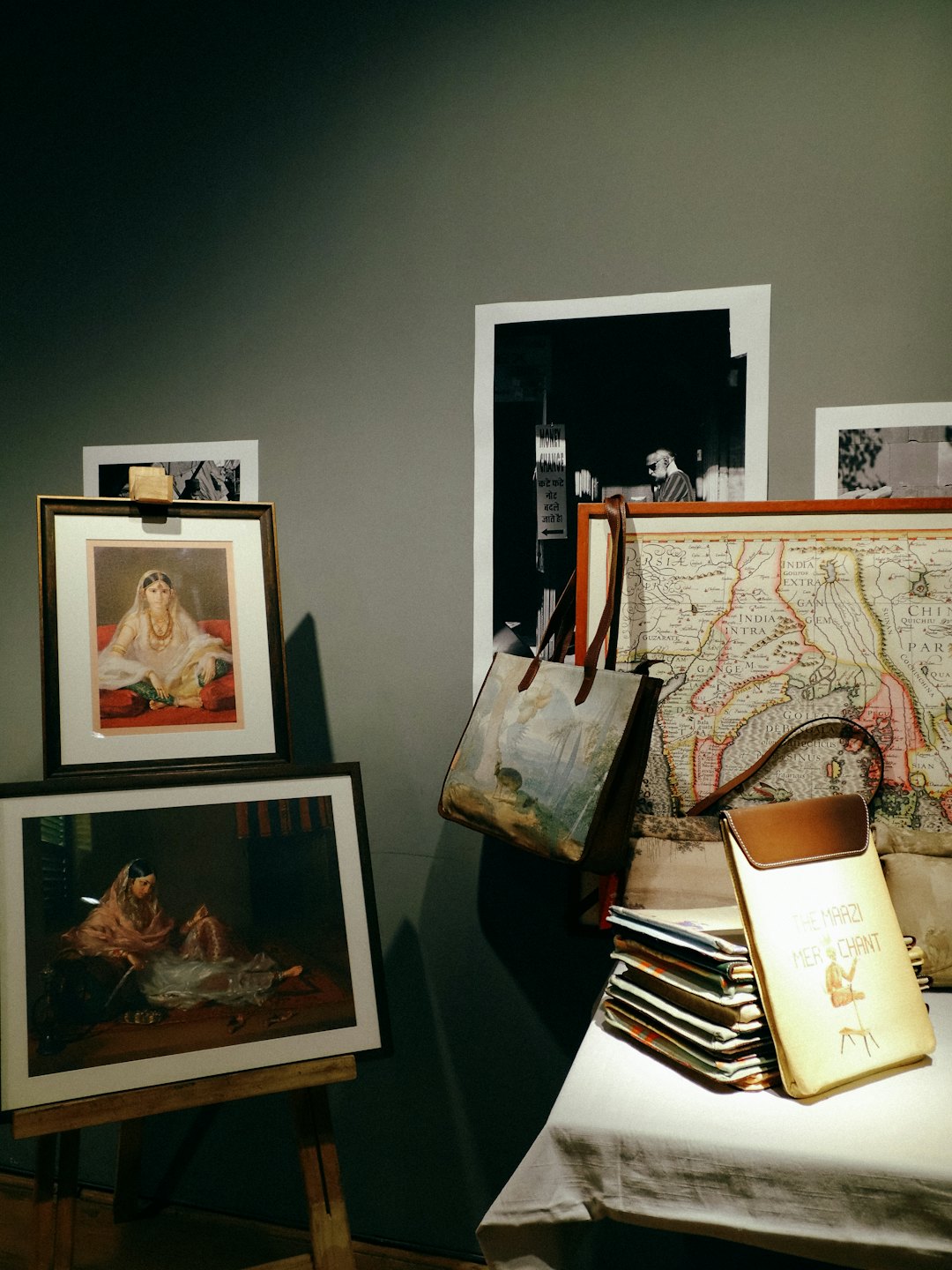 Framed portraits and vintage map displayed on a draped table.