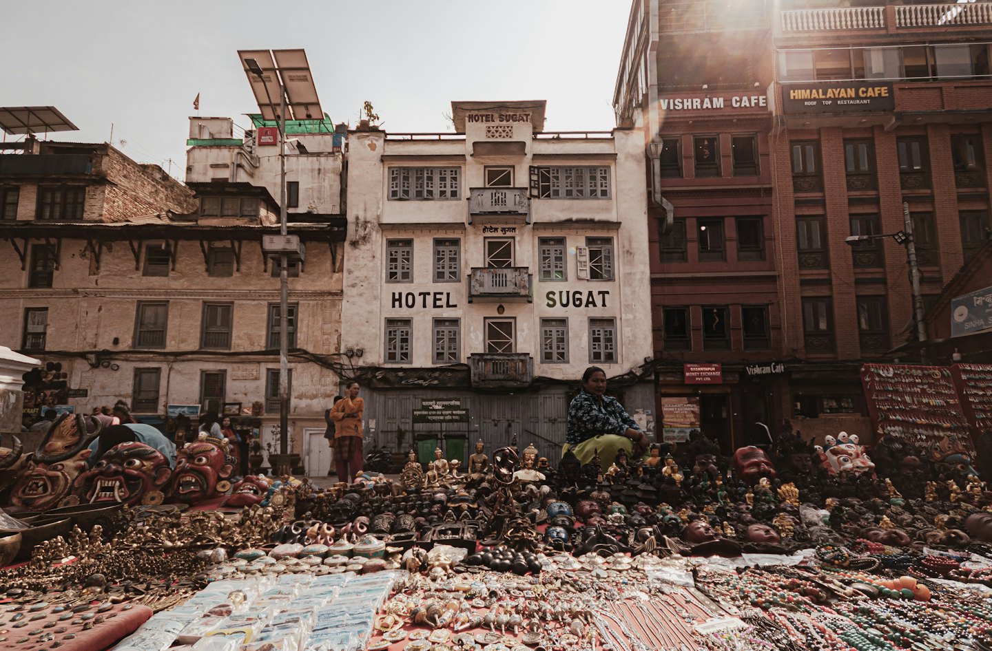 Two women sell artisanal goods at an outdoor street market.